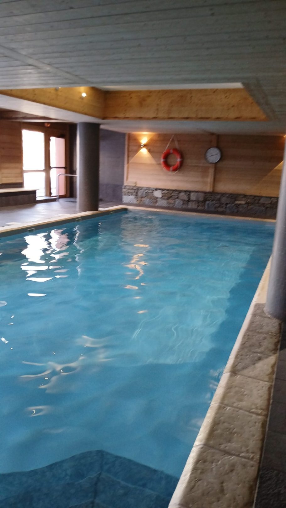 Piscine intérieure avec eau claire, éclairage doux et murs en pierre.