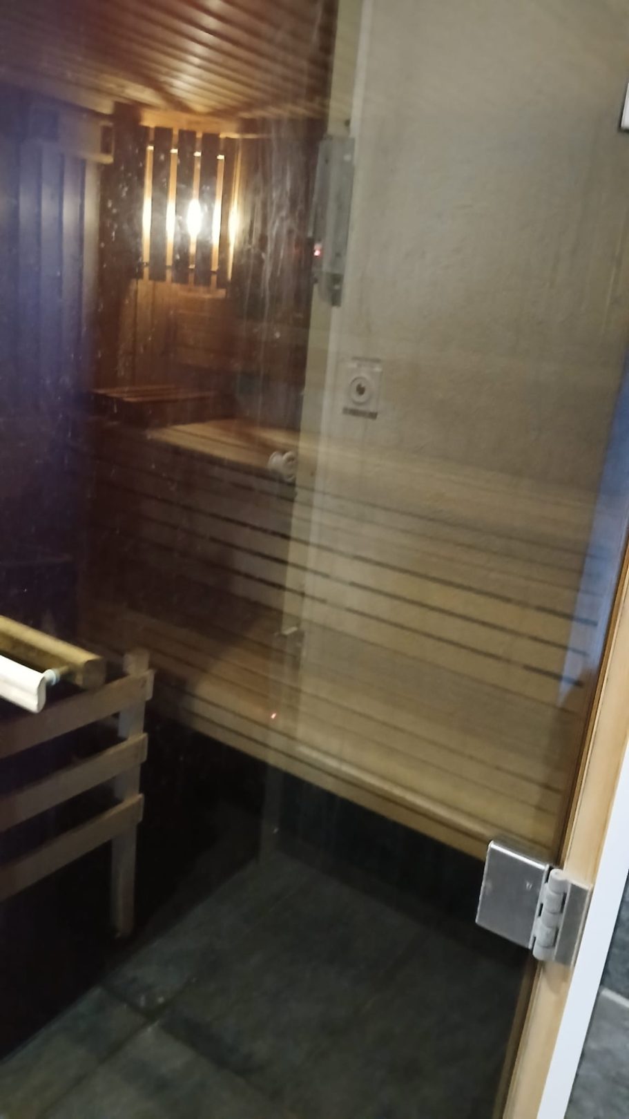 Sauna en bois avec bancs, éclairage doux et murs en bois, portes en verre.