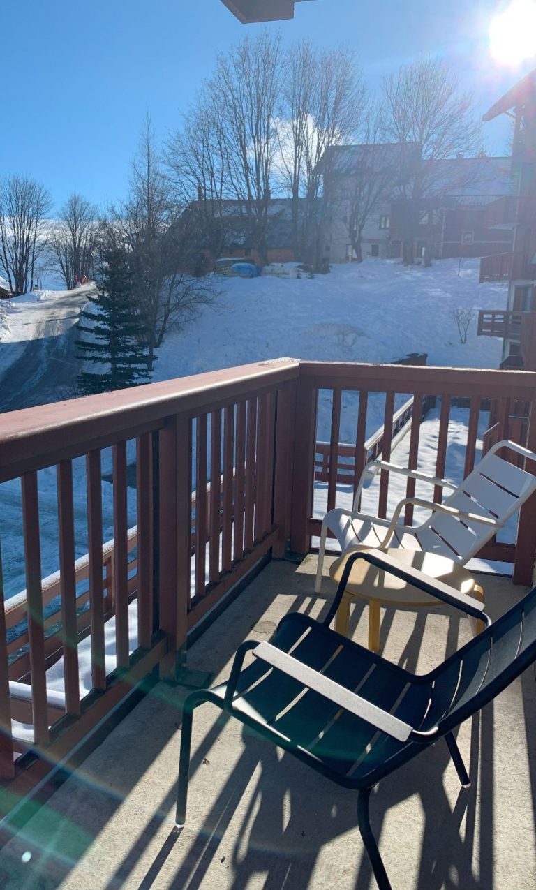 Balcon Balcon avec chaises surplombant une neige immaculée et le soleil brillant.